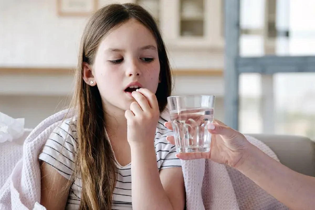 دختری که یک قرص می خورد و فردی یک لیوان برای او نگه داشته است