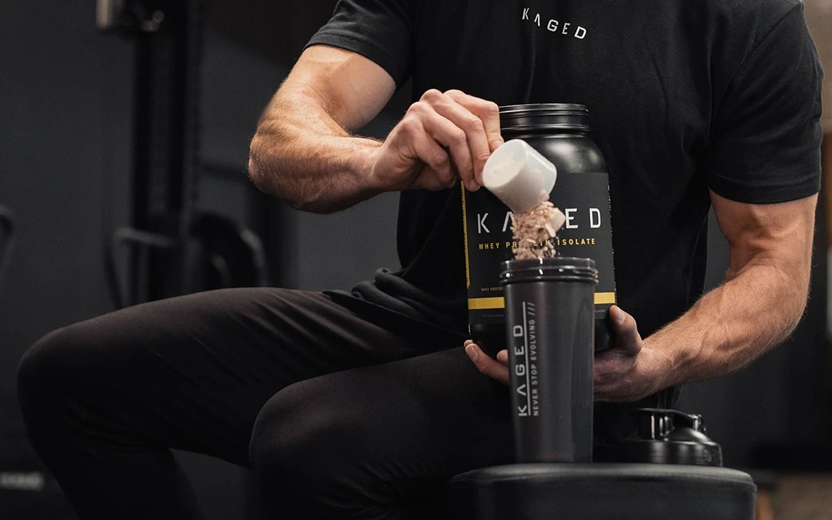 دستان مردی که شیشه مکمل بدنسازی جلوی او قرار گرفته و او در حال خالی کردن مکمل داخل شیشه آب خود است