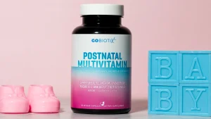 یک جفت کفش نوزاد در سمت چپ، یک قوطی مولتی ویتامین بعد از زامیان در وسط تصویر و بلوک های پلاستیکی آبی در سمت راست که روی آنها حروف B، A، B، نوشته شده است Y