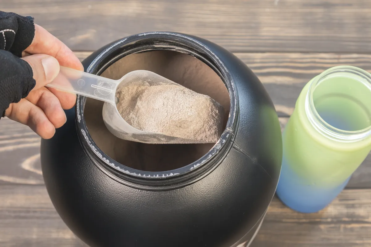 فردی که از قوطی مکمل گینر، پودر مکمل خالی می کند