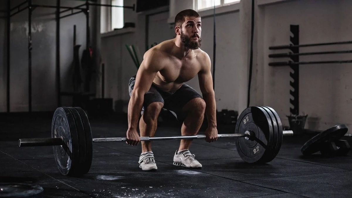 مرد بدنسازی در حال بلند کردن وزنه از روی زمین