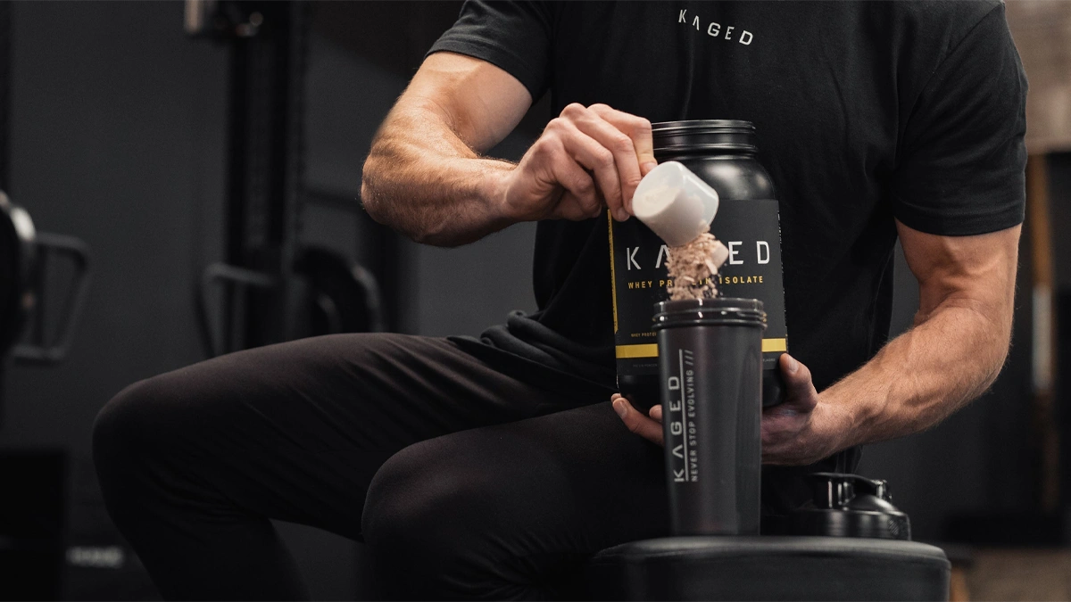 مردی که روی نیمکت نشسته است و داخل قمقمه پودر مکمل بدنسازی خالی می کند