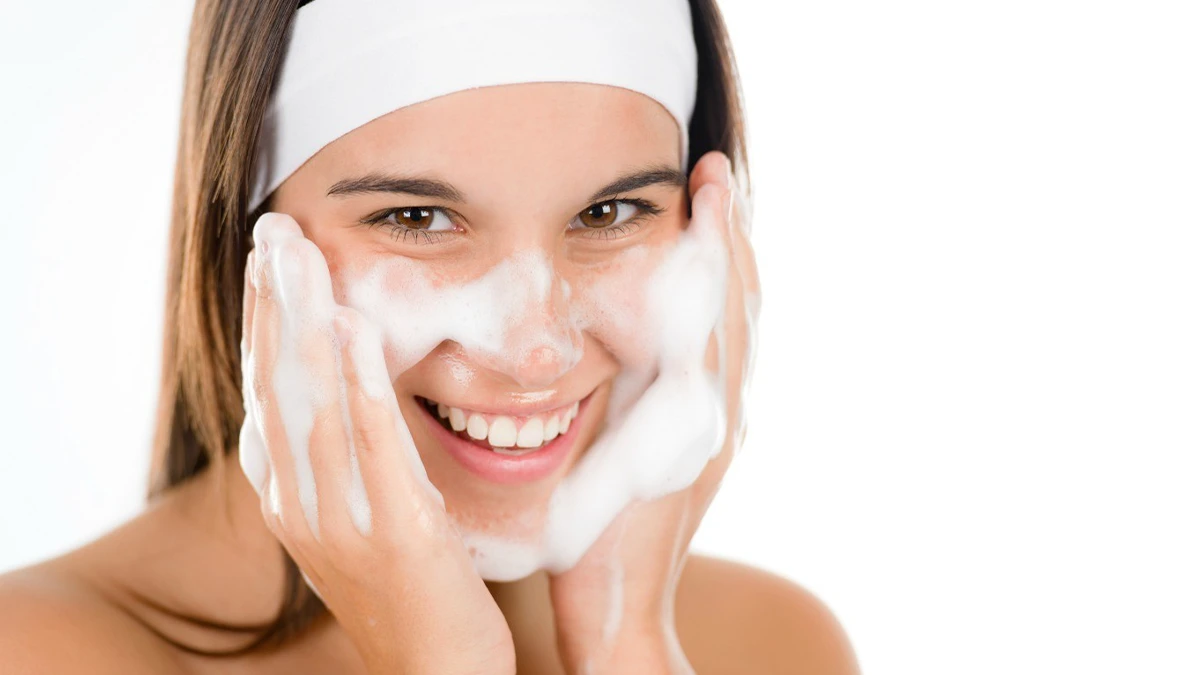 دختری که می خندد و با دست کف به صورتش می مالد