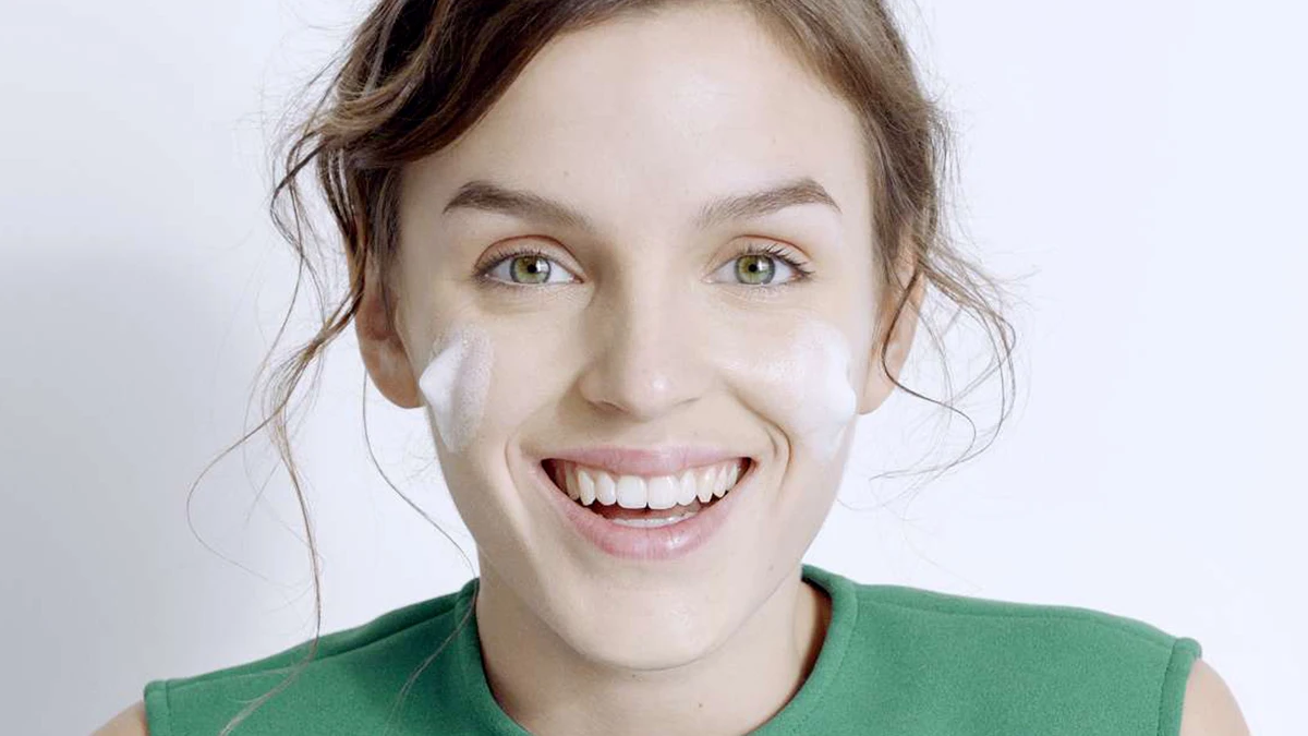 دختری که می خندد و روی گونه هایش شوینده مالیده است