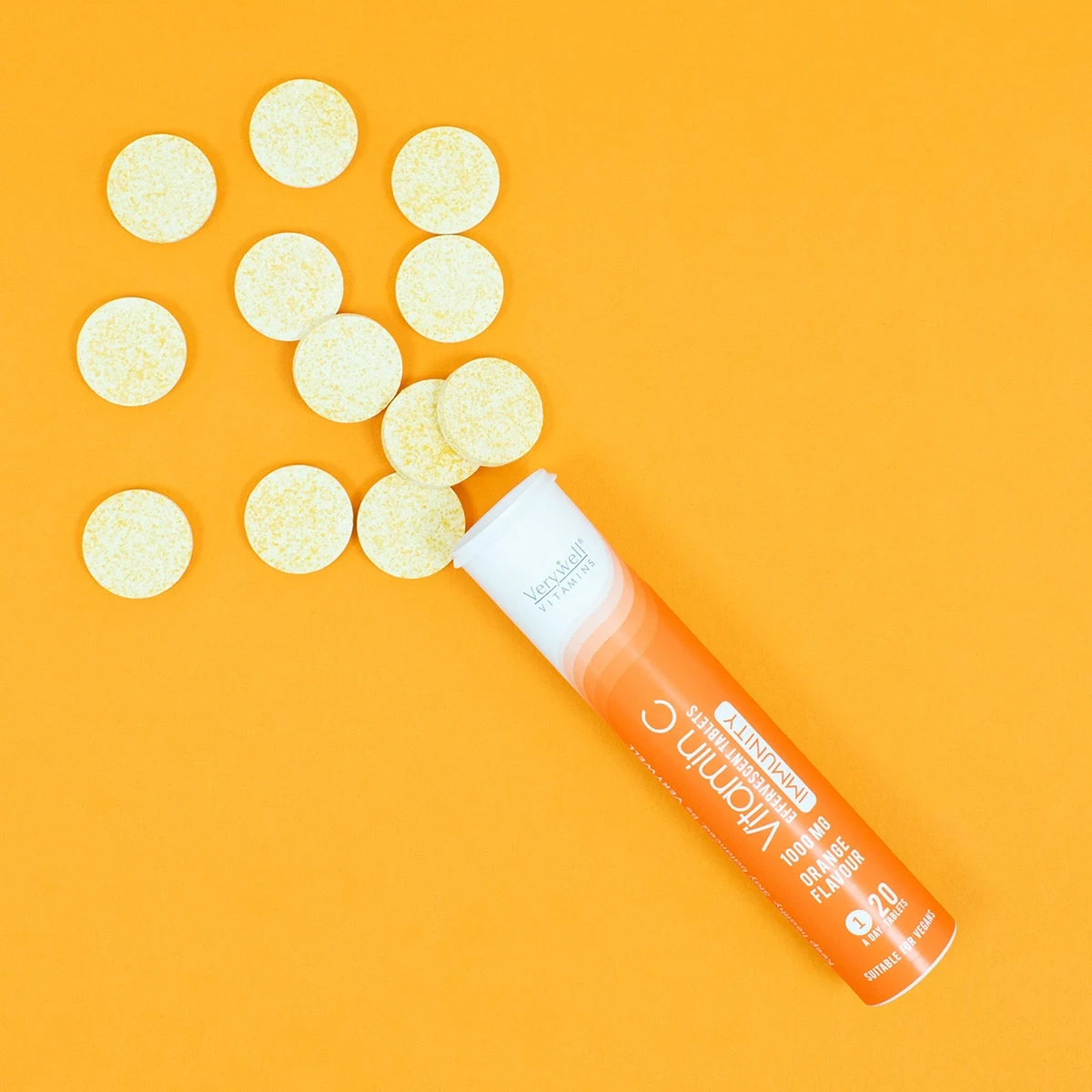 قوطی قرص ویتامین سی که چند قرص از آن بیرون ریخته است