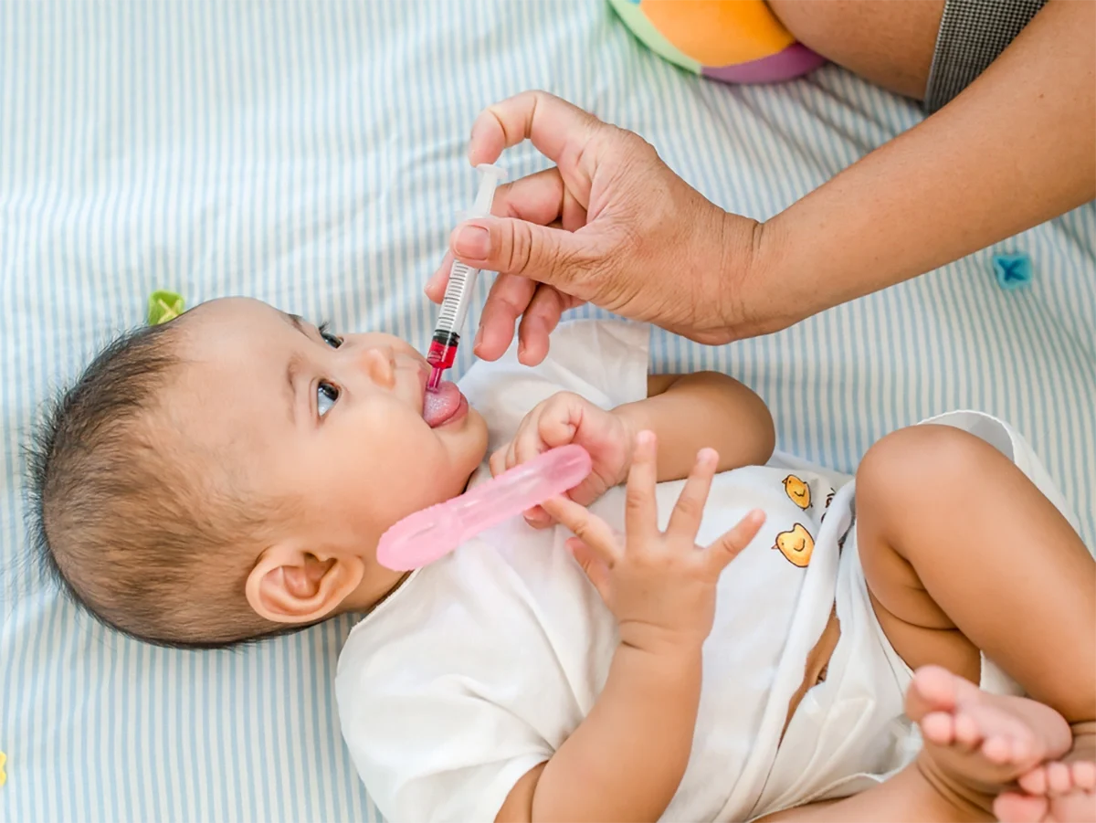 نوزادی که مادرش با قطره چکان به او قطره مولتی ویتامین می دهد