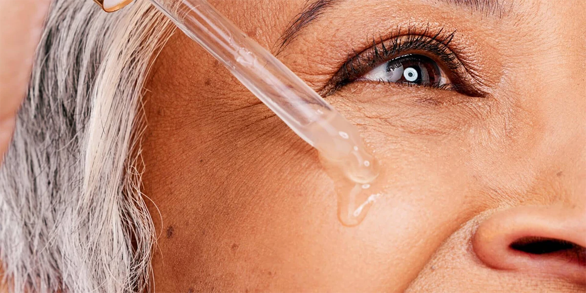 عکس نزدیک از صورت زن که روی گونه راست خود از سرم پوستی استفاده می کند